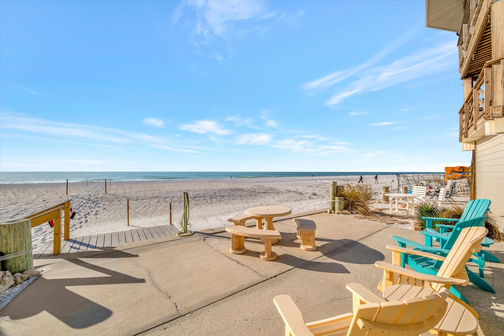 Beachfront property with direct access to sandy shores and ocean views. Outdoor patio area features colorful Adirondack chairs, picnic table, and private beach access in a coastal setting.