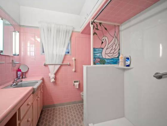 Step into your private bathroom, where cheerful pink tiles and vintage charm create a playful, nostalgic retreat. The whimsical swan art adds a unique touch of character to this one-of-a-kind space.
