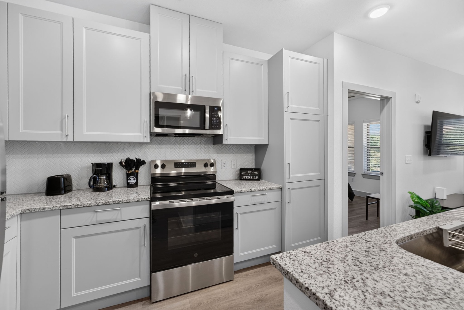 Step into your fully equipped kitchen where crisp white cabinetry and granite countertops set the stage for easy meal prep. Modern appliances and thoughtful design make cooking feel effortless.