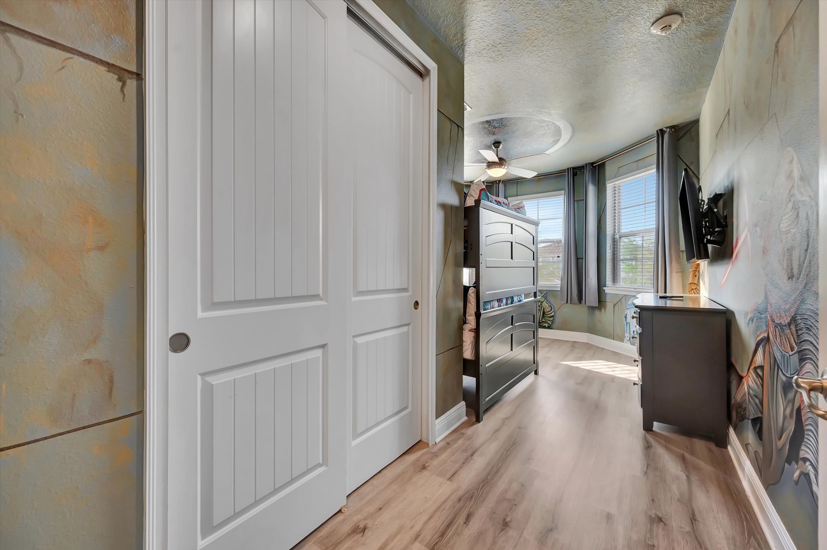 Step into coastal-inspired comfort with soft ocean-toned walls and warm wood floors. Natural light fills your space through windows that open onto scenic views, while a ceiling fan keeps you cool and comfortable.