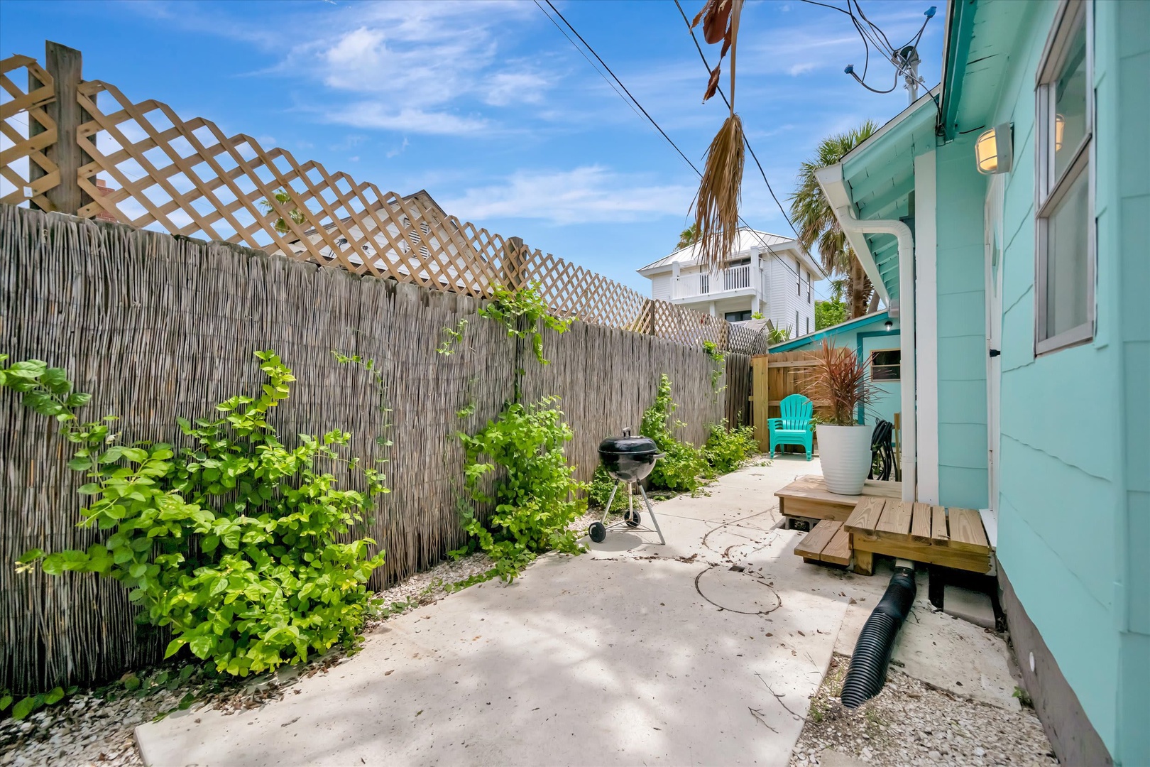 Your private outdoor space features a charming garden path, BBQ grill for coastal cookouts, and lush greenery creating a peaceful retreat just steps from your door.