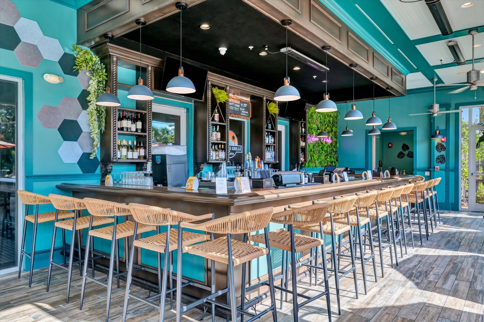 This vibrant bar and lounge area features modern design with turquoise walls, stylish pendant lighting, and comfortable seating where you can unwind with your favorite drinks.