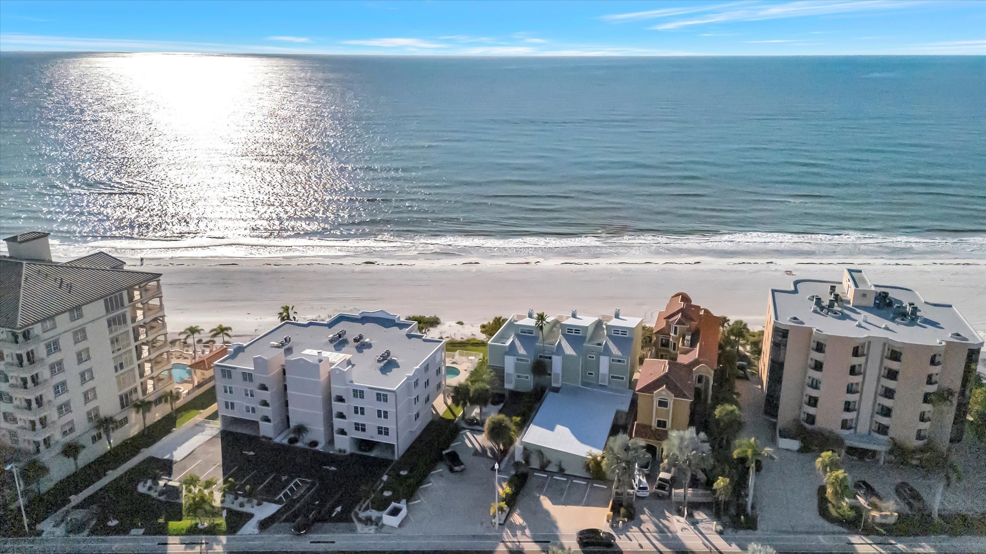 Aerial view of beachfront properties along pristine white sand and sparkling turquoise waters. The property is situated in an idyllic coastal setting.
