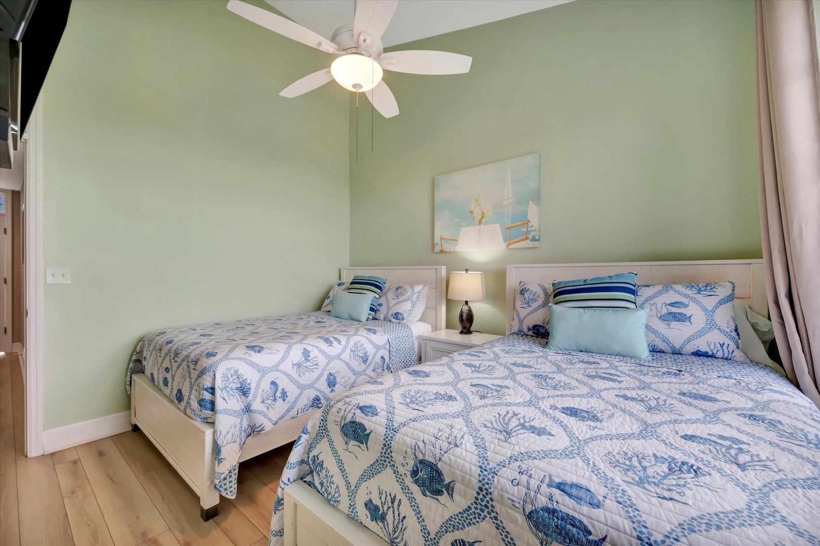 Your peaceful coastal escape awaits with two plush beds dressed in soothing ocean blues. The ceiling fan keeps you cool while soft light warms the space.