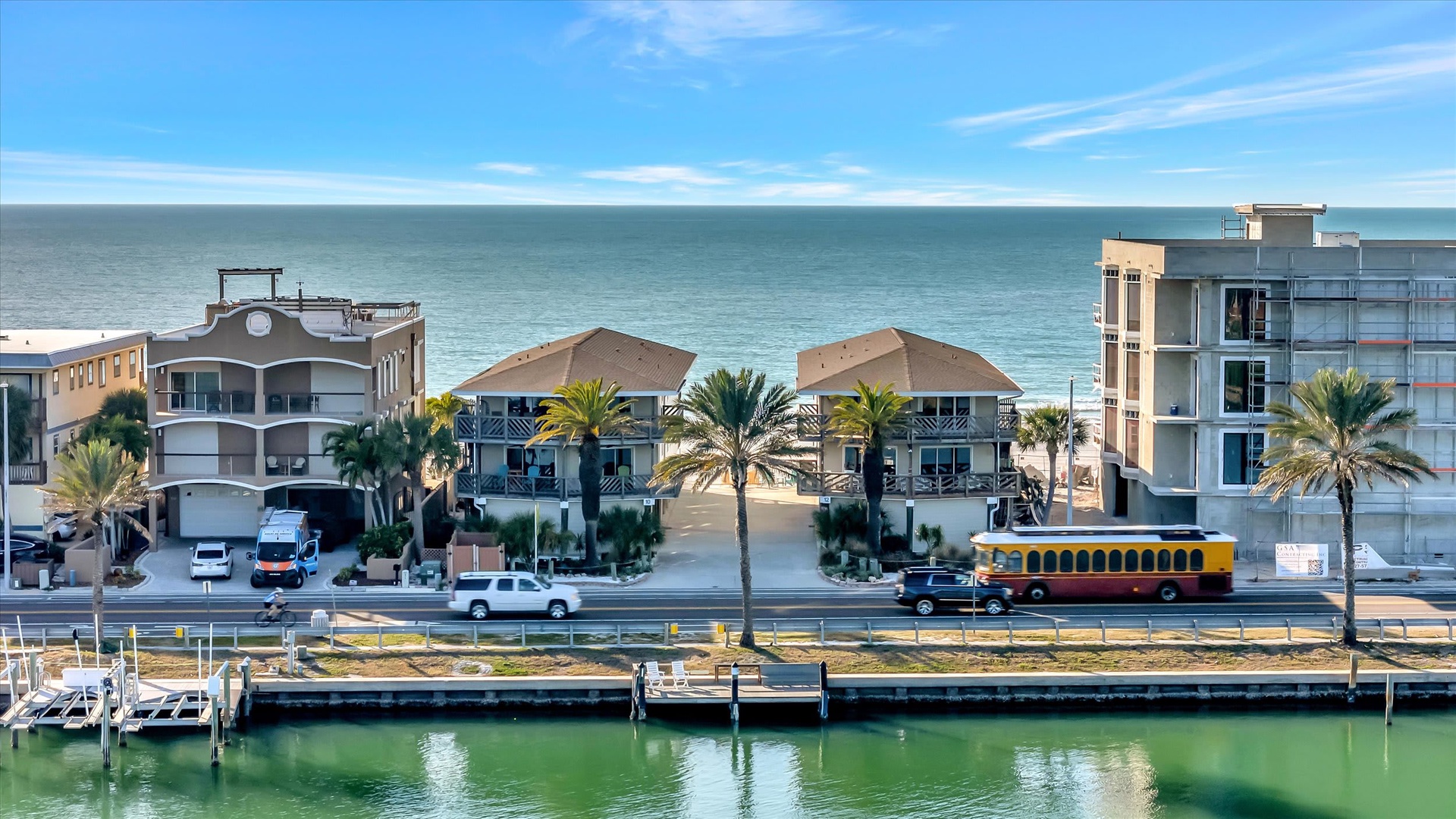 Beachfront properties nestled between calm harbor waters and the open ocean, surrounded by swaying palms and endless coastal views.