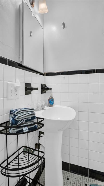 This bathroom offers classic black-and-white tile styling, a pedestal sink, and fresh towels waiting for you to settle in and freshen up.
