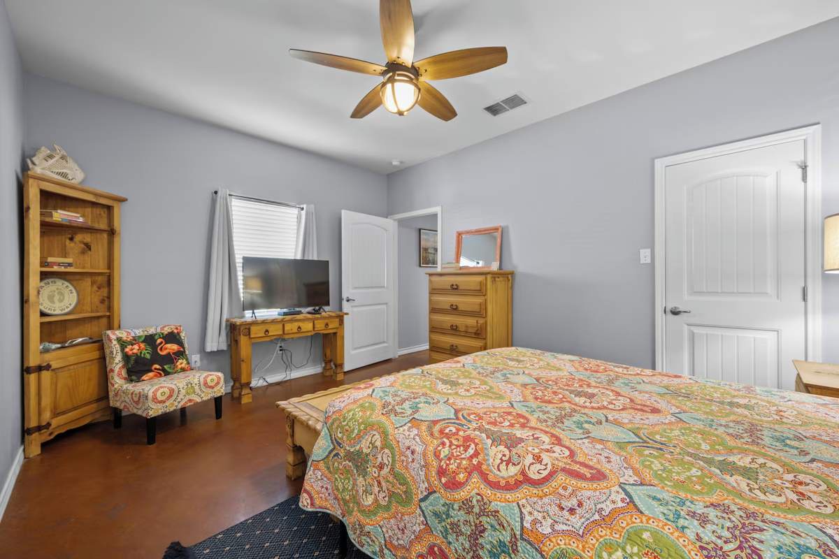 Sink into your comfortable bed under the gentle breeze of the ceiling fan. Charming wooden furniture and pops of color create a cozy, homey retreat where you'll drift off to restful sleep.