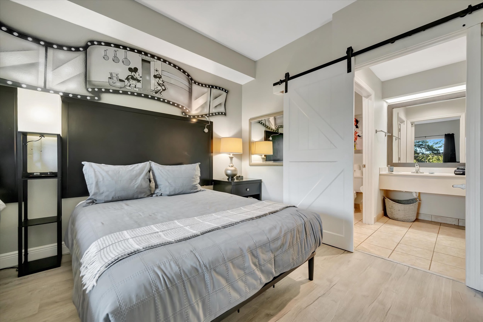 Your cozy bedroom features a comfortable queen bed, charming barn door, and vintage movie-themed décor with warm lighting—perfect for unwinding after your day.