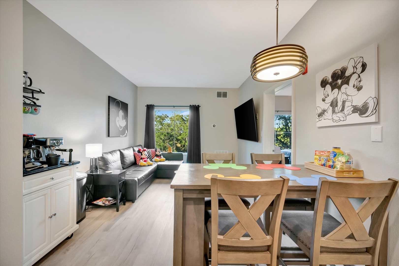 Bright, open living space with vaulted ceilings, perfect for family gatherings. Large windows flood the room with natural light and leafy views, creating a welcoming retreat.