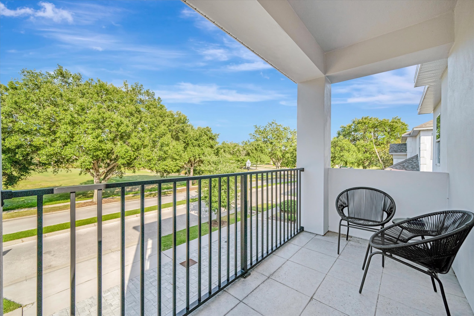 Your private balcony offers a peaceful spot to unwind with morning coffee or evening conversation, overlooking leafy trees and a quiet residential street below.