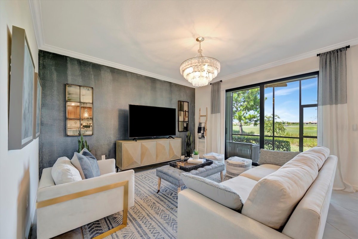 Unwind in this bright, airy living room where plush seating invites you to relax beneath a stunning chandelier. Floor-to-ceiling windows frame serene landscape views, perfect for your quiet moments.
