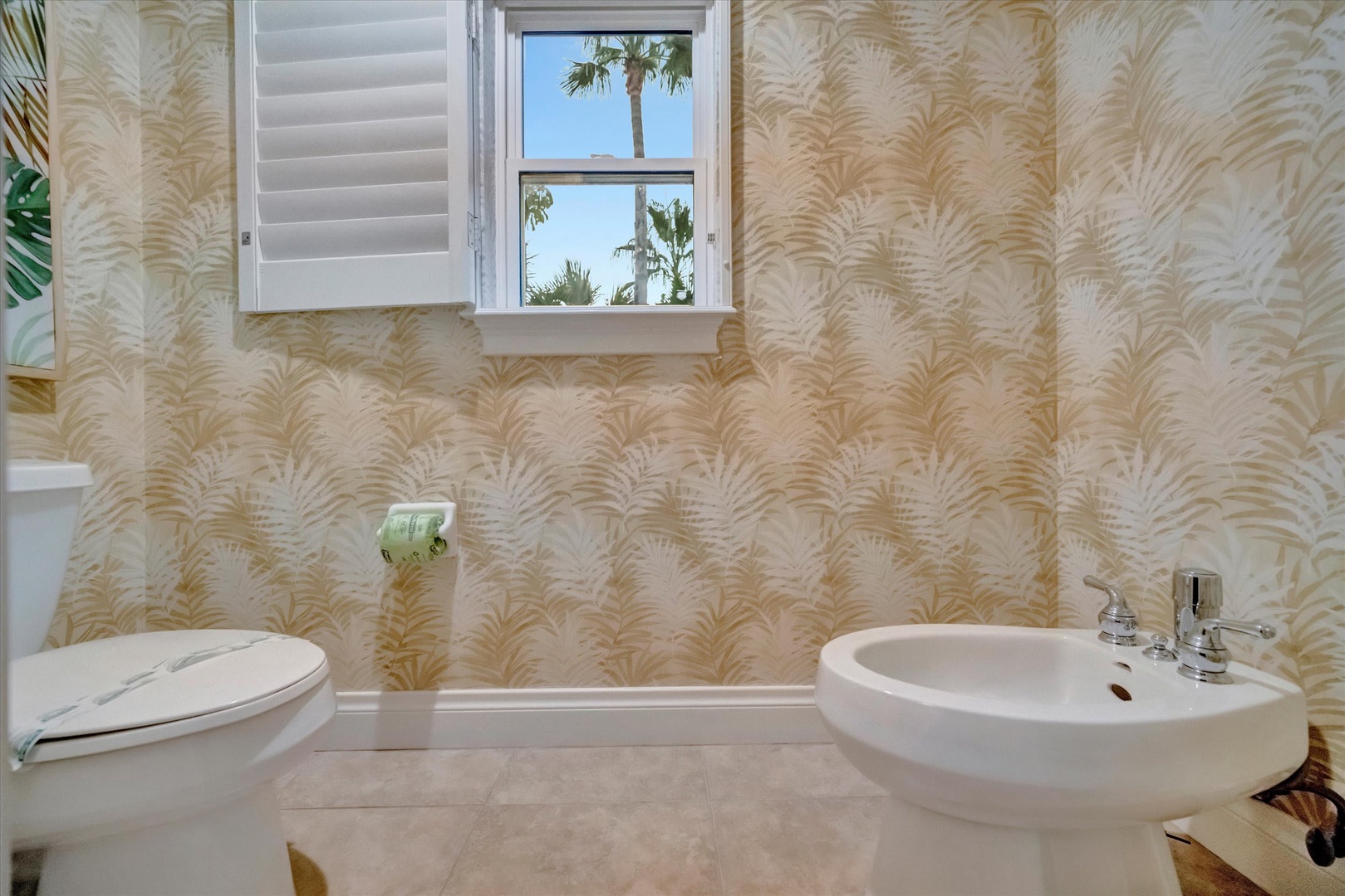 Step into your private oasis—this bathroom features tropical-inspired wallpaper and a bright window with palm tree views that brings the outdoors in.