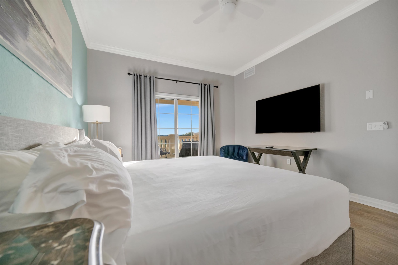 Sink into crisp white bedding and wake up to natural light streaming through your window. This serene bedroom features a cozy workspace and entertainment setup for your comfort.