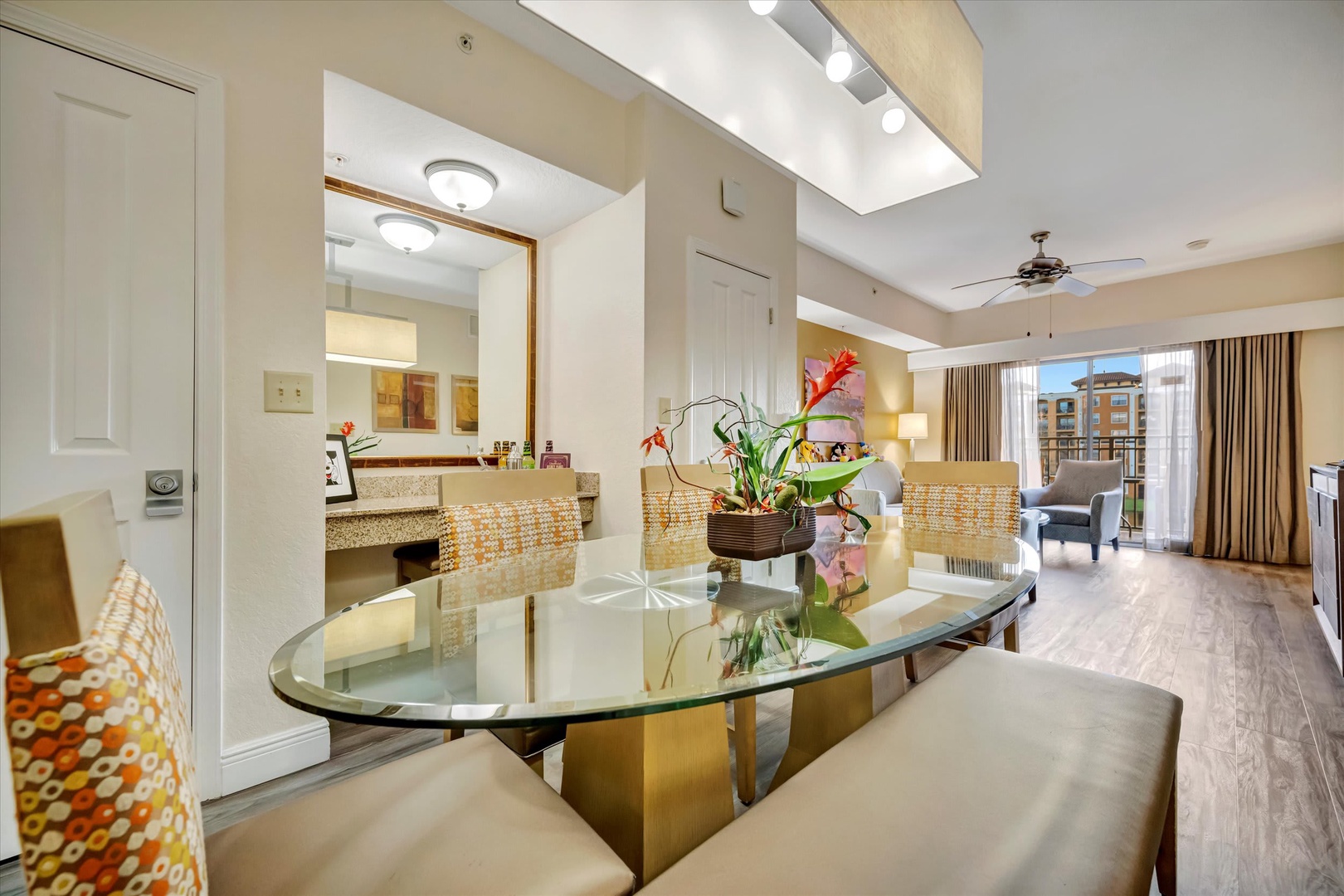 Step into your spacious suite where natural light fills the open living and dining areas. A stylish glass table and cheerful floral centerpiece welcome you home after exploring the city.