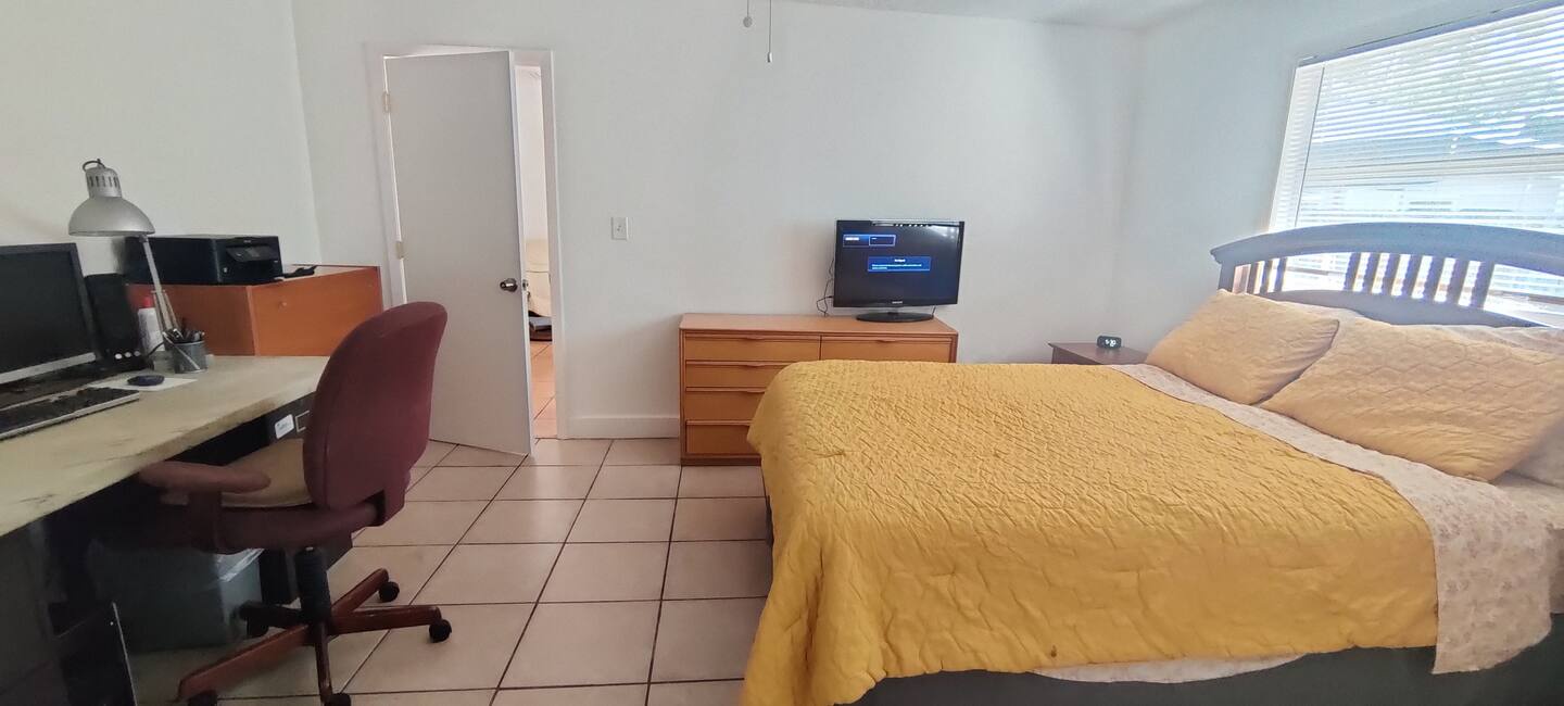 Settle into your comfortable bedroom with a cheerful golden bedspread, dedicated workspace with dual monitors, and all the essentials for a relaxing stay.