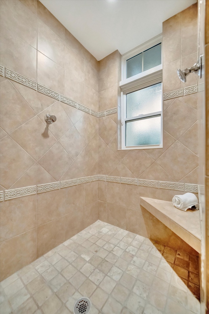 Step into your elegant tiled shower, where warm beige tones and decorative accents create a spa-like retreat after a day of exploring.