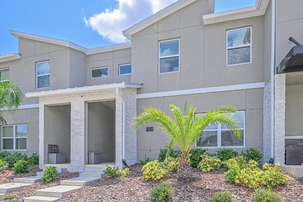 A modern townhome facade with clean lines and bright Florida sunshine welcomes your arrival. Tropical palms and low-maintenance landscaping frame the covered entry—effortlessly stylish and ready for your vacation.