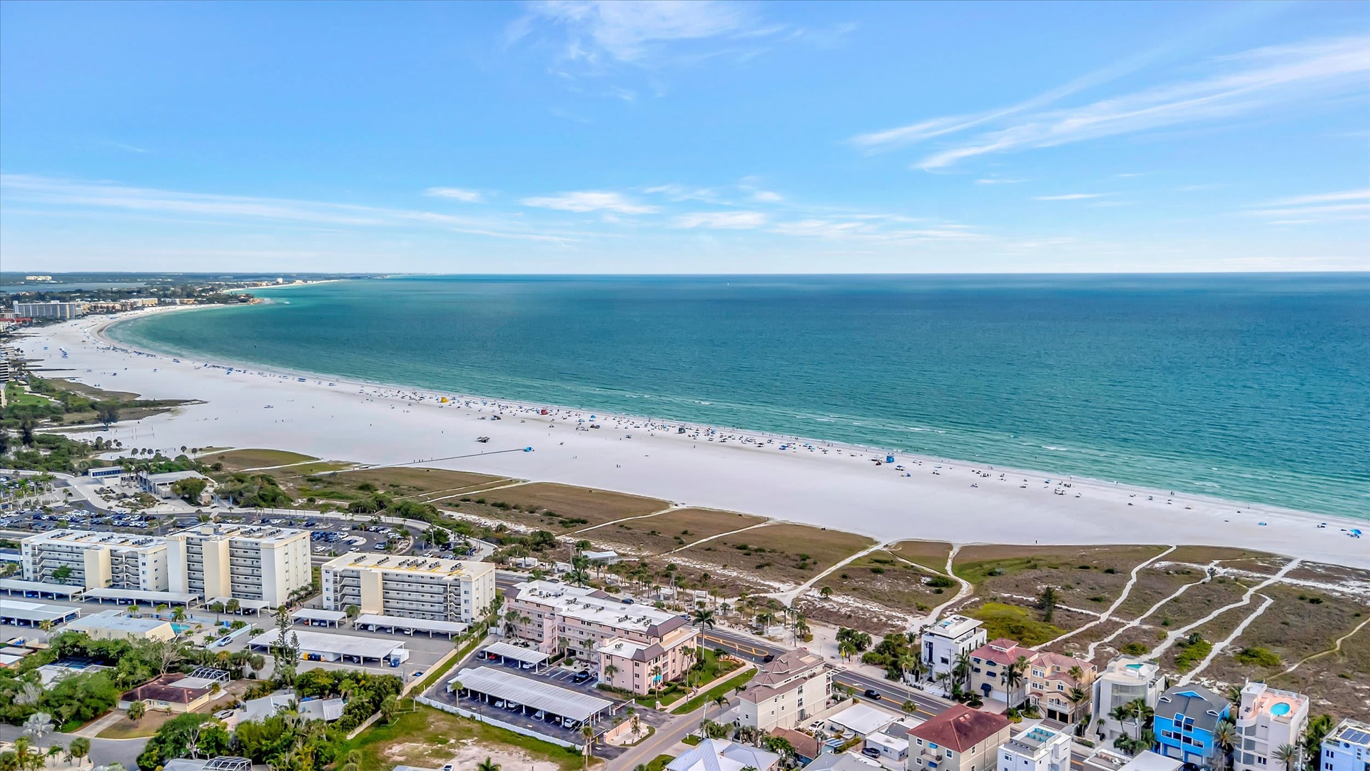 Aerial view of the beachfront property area, showcasing pristine white sand beaches stretching along turquoise Gulf waters and the surrounding coastal neighborhood.