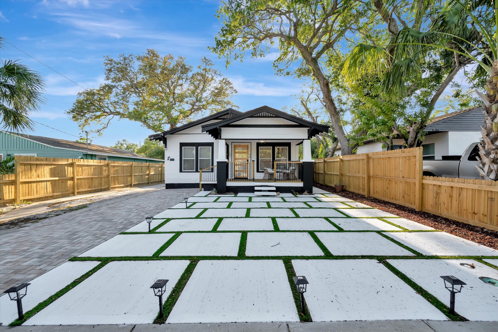 Modern tropical home with private driveway, covered porch, and lush mature trees surrounding the property in a quiet residential setting.