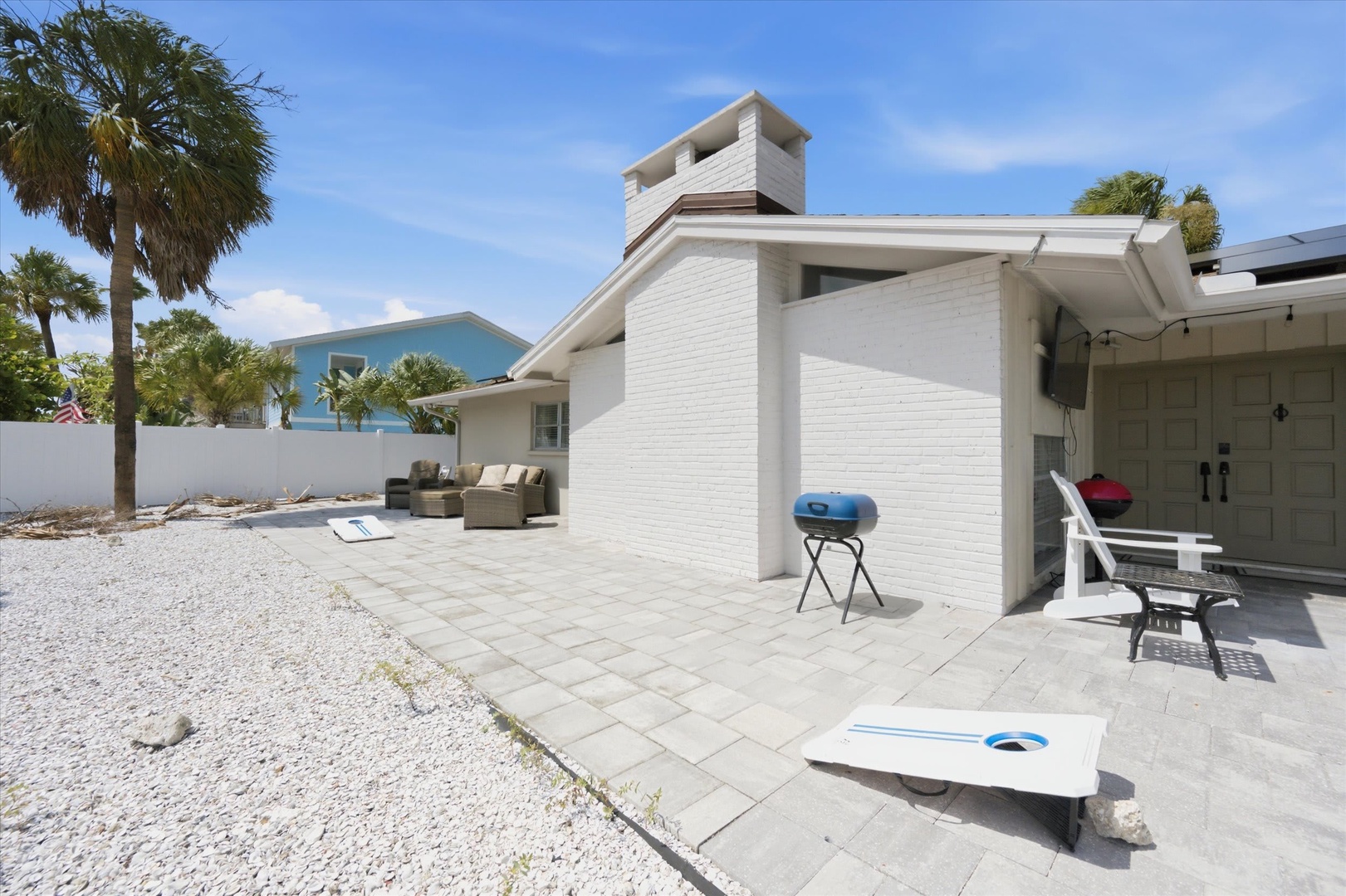 Modern beachside property with spacious paved patio, palm trees, and outdoor seating perfect for coastal living and entertaining.