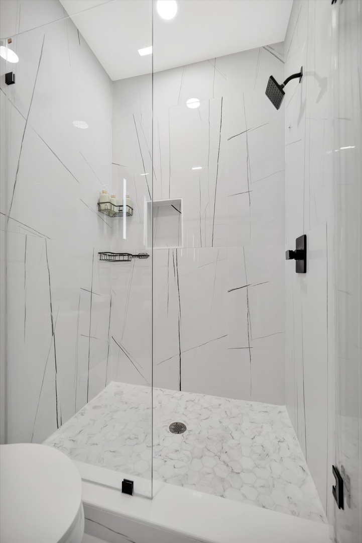 Step into your private rain shower, where sleek marble-look tile and contemporary fixtures create a spa-like retreat for your morning routine.