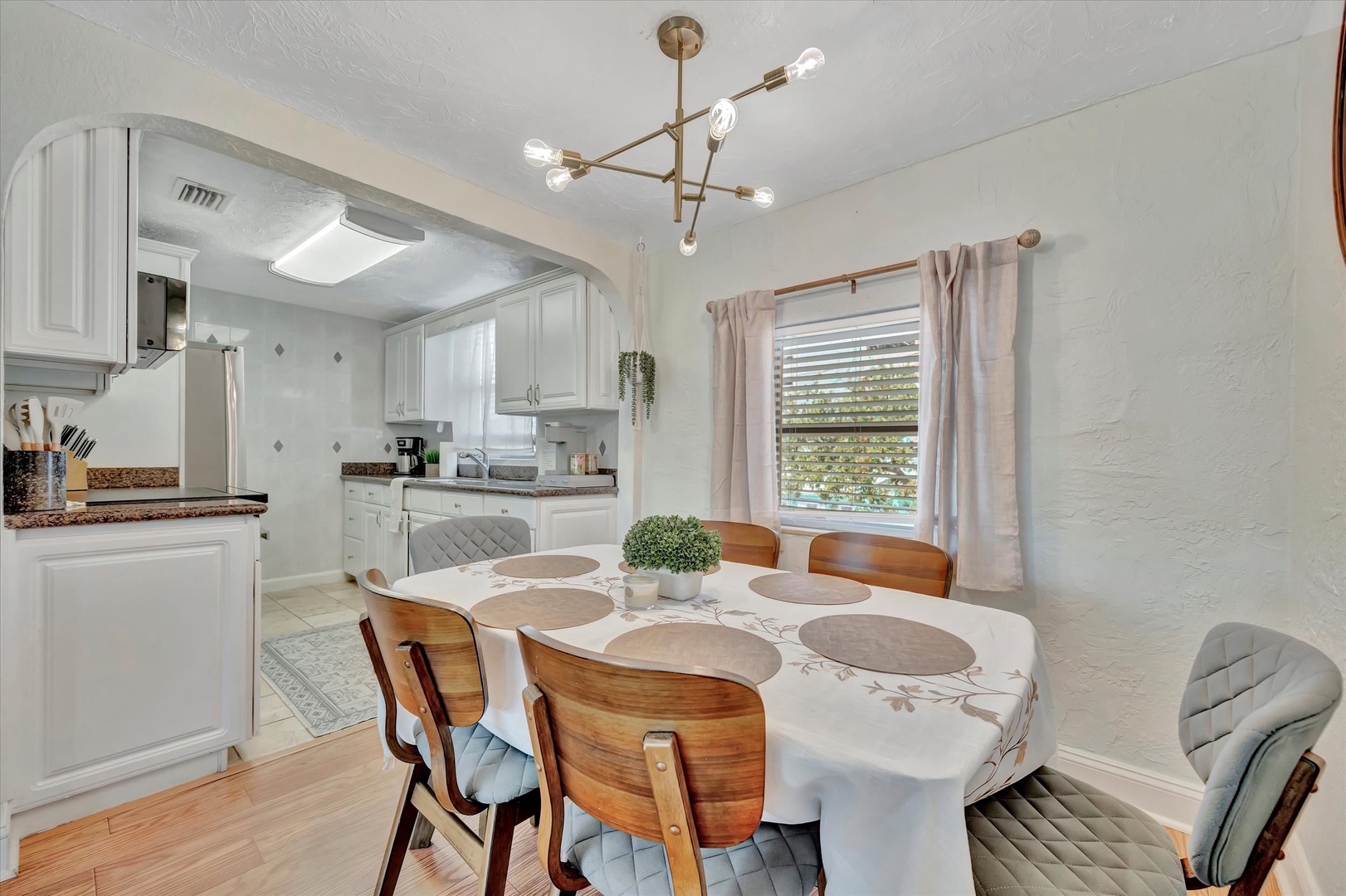 Gather around your inviting dining table, set beneath warm modern lighting and open to the fully-equipped kitchen. Enjoy meals together in this comfortable, sunlit space that makes every breakfast or dinner feel special.