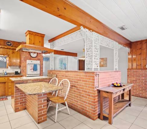 Gather around the charming brick breakfast bar or prep your favorite meals in this spacious kitchen with warm wood accents and plenty of counter space for cooking together.