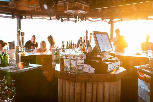 Sip your favorite cocktail at the tiki bar as golden light spills across the scene, creating the perfect backdrop for relaxed afternoons by the water.