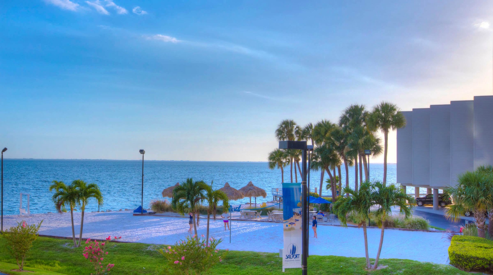 The property sits directly on the water, surrounded by swaying palms and lush tropical landscaping. Your beachfront escape features both sandy shores and sparkling pool areas, all bathed in warm coastal sunlight.