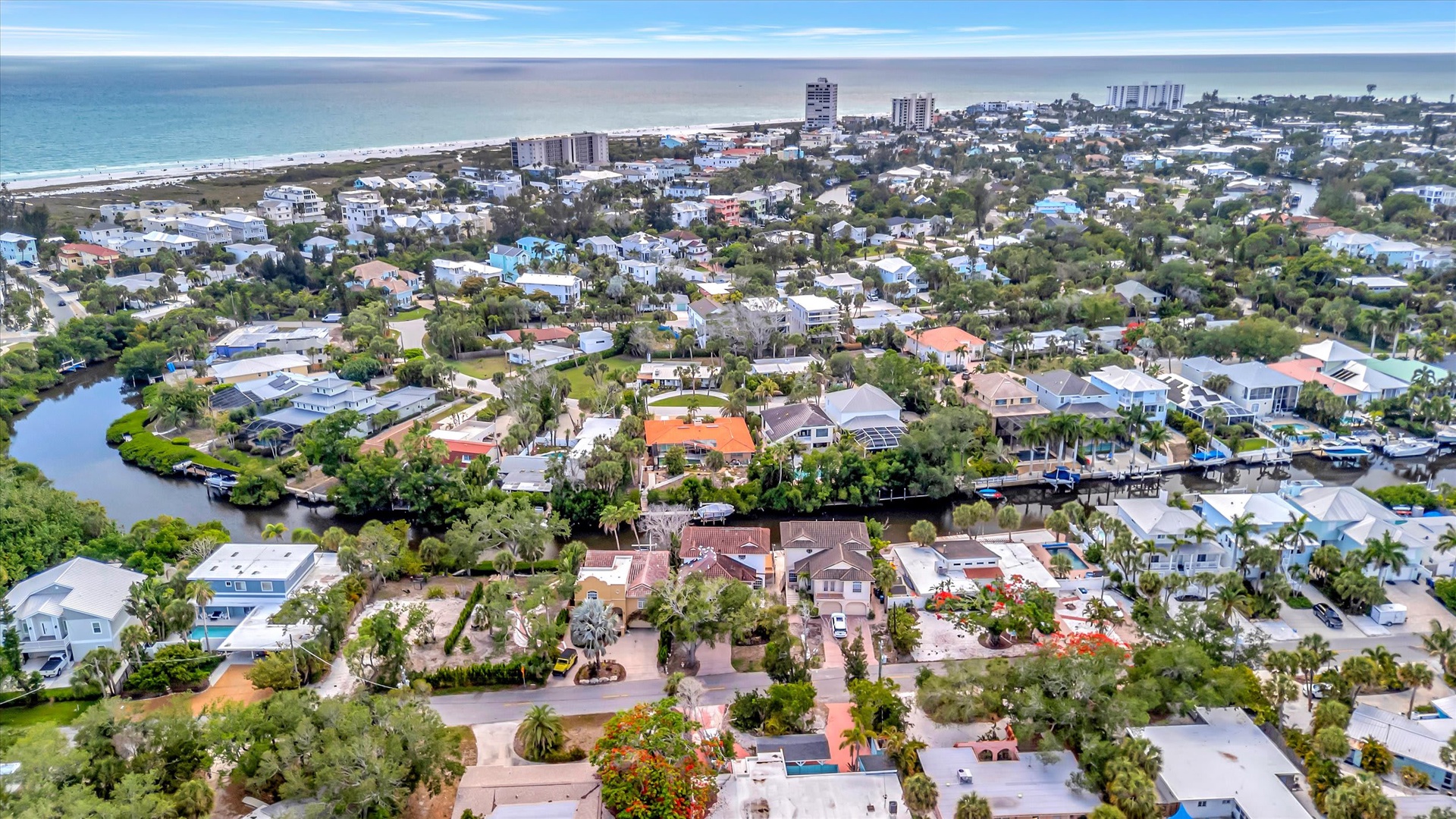 Aerial view of a coastal residential neighborhood, with the property situated between tranquil waterways and the Gulf of Mexico beaches just beyond.