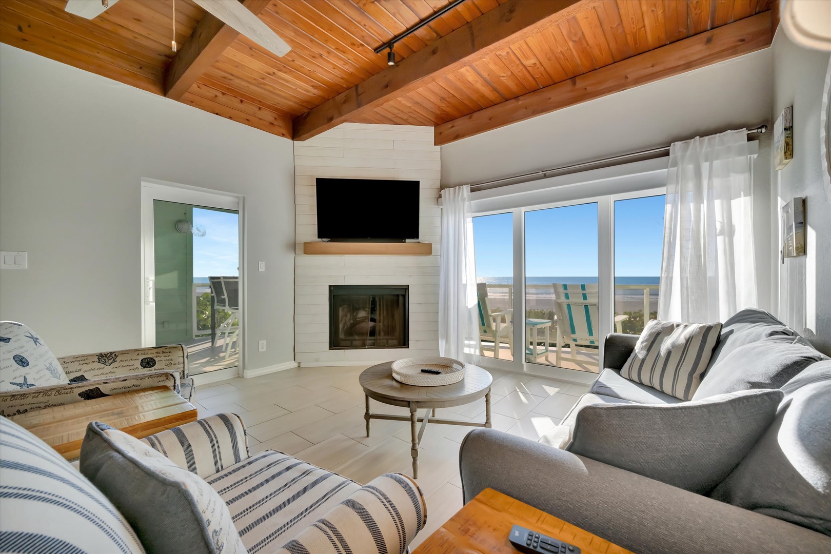 Relax in your bright, airy living room where warm wood ceilings meet crisp coastal style. Sink into plush seating and enjoy the cozy fireplace while the ocean stretches endlessly beyond your windows.