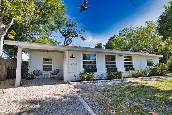 A classic single-story home surrounded by mature trees and lush greenery, with a welcoming front porch ready for your arrival.