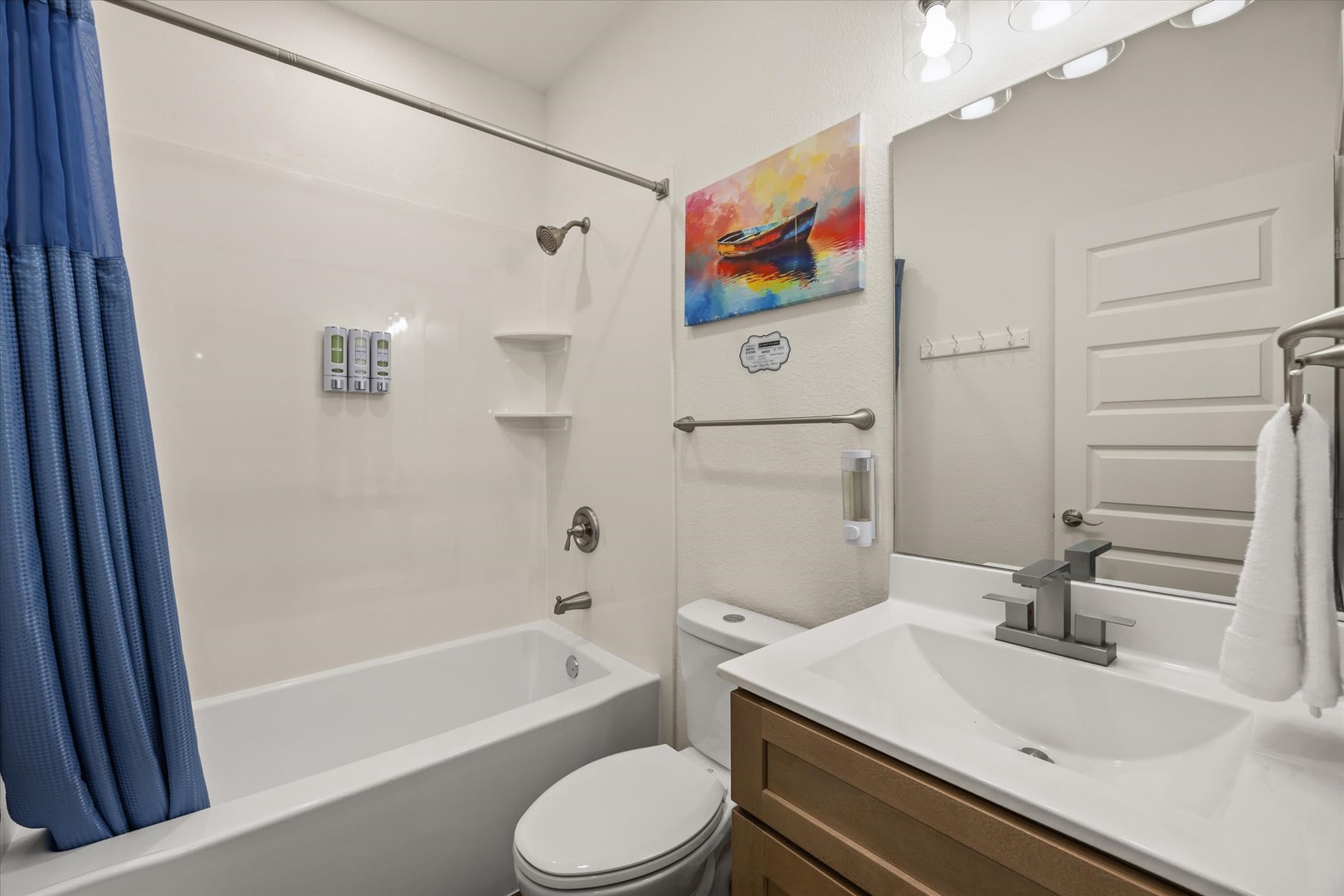 Your private bathroom offers a full tub-shower combo, crisp white finishes, and thoughtful touches like built-in shelving and fluffy towels—all you need to unwind after a day of exploring.