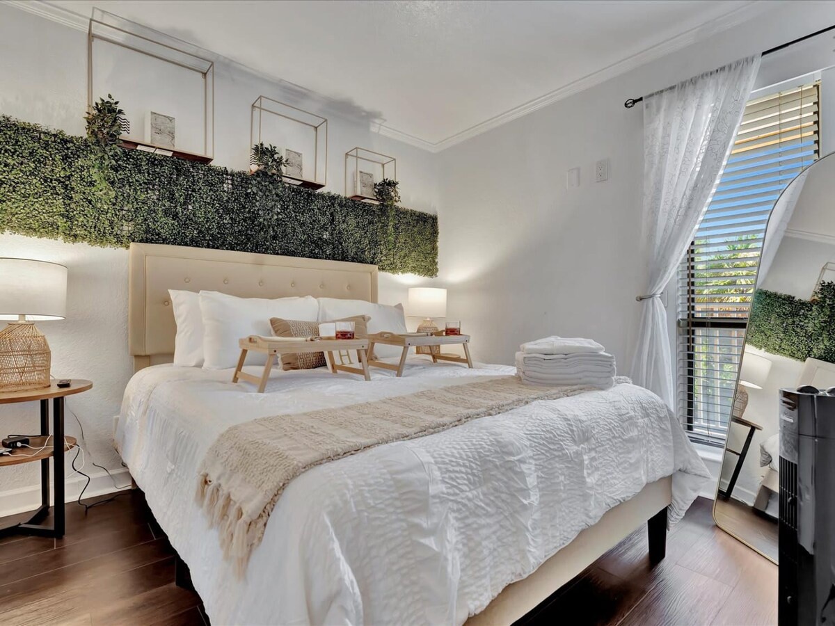 Drift into peaceful rest in your serene bedroom, where soft linens invite relaxation and living greenery brings the calm of nature indoors, all bathed in gentle natural light.