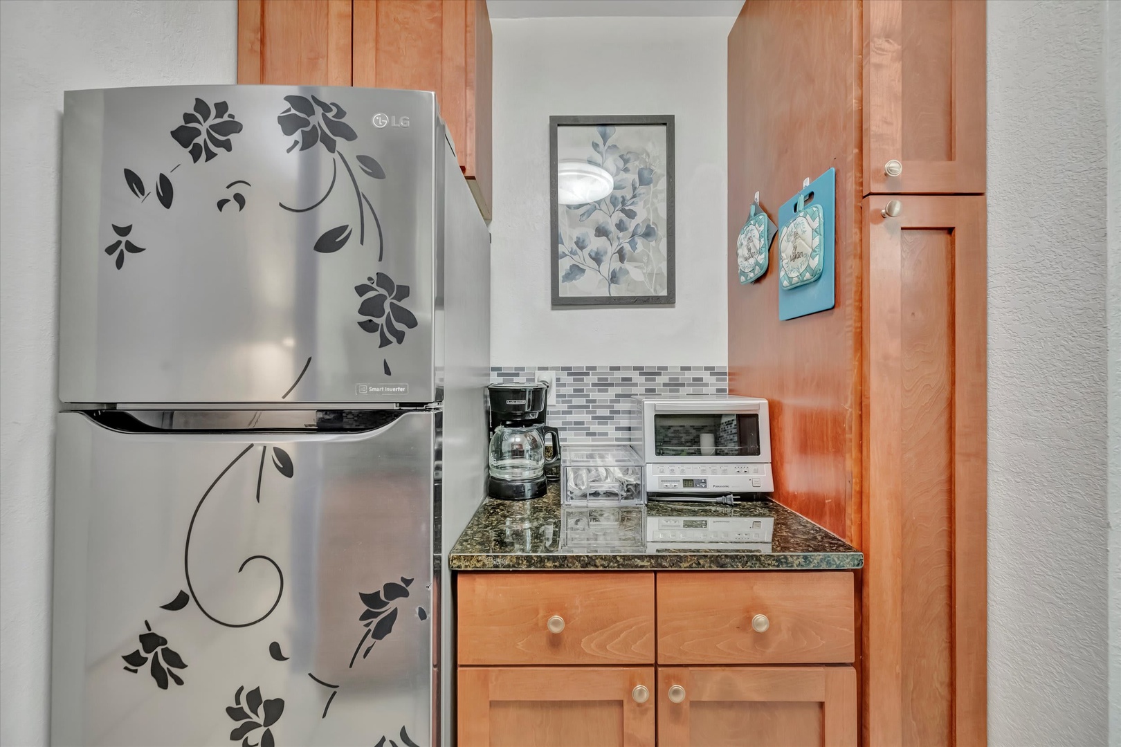 Your fully equipped kitchenette features charming wood cabinetry, granite countertops, and everything you need to prepare quick meals—coffee maker, microwave, and a stylish floral fridge add practical touches and personality.