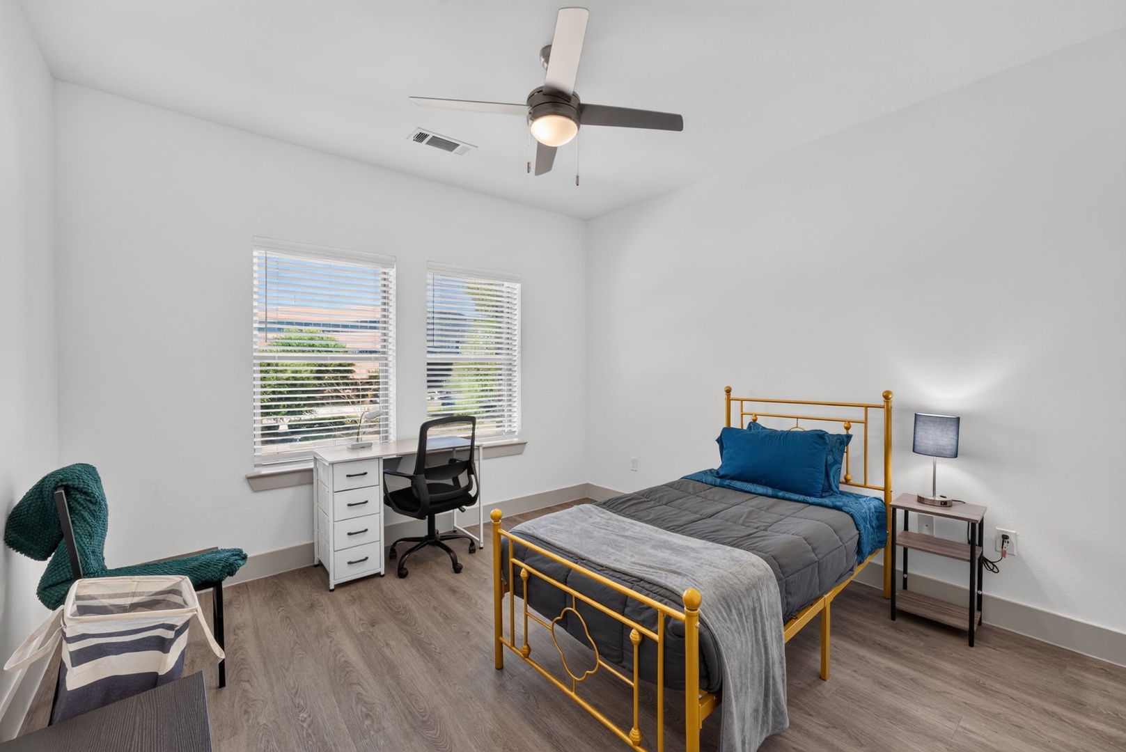Settle in and make yourself at home in this bright, airy bedroom. Natural light streams through large windows, while the ceiling fan keeps you cool. Your workspace and a cozy reading chair await.
