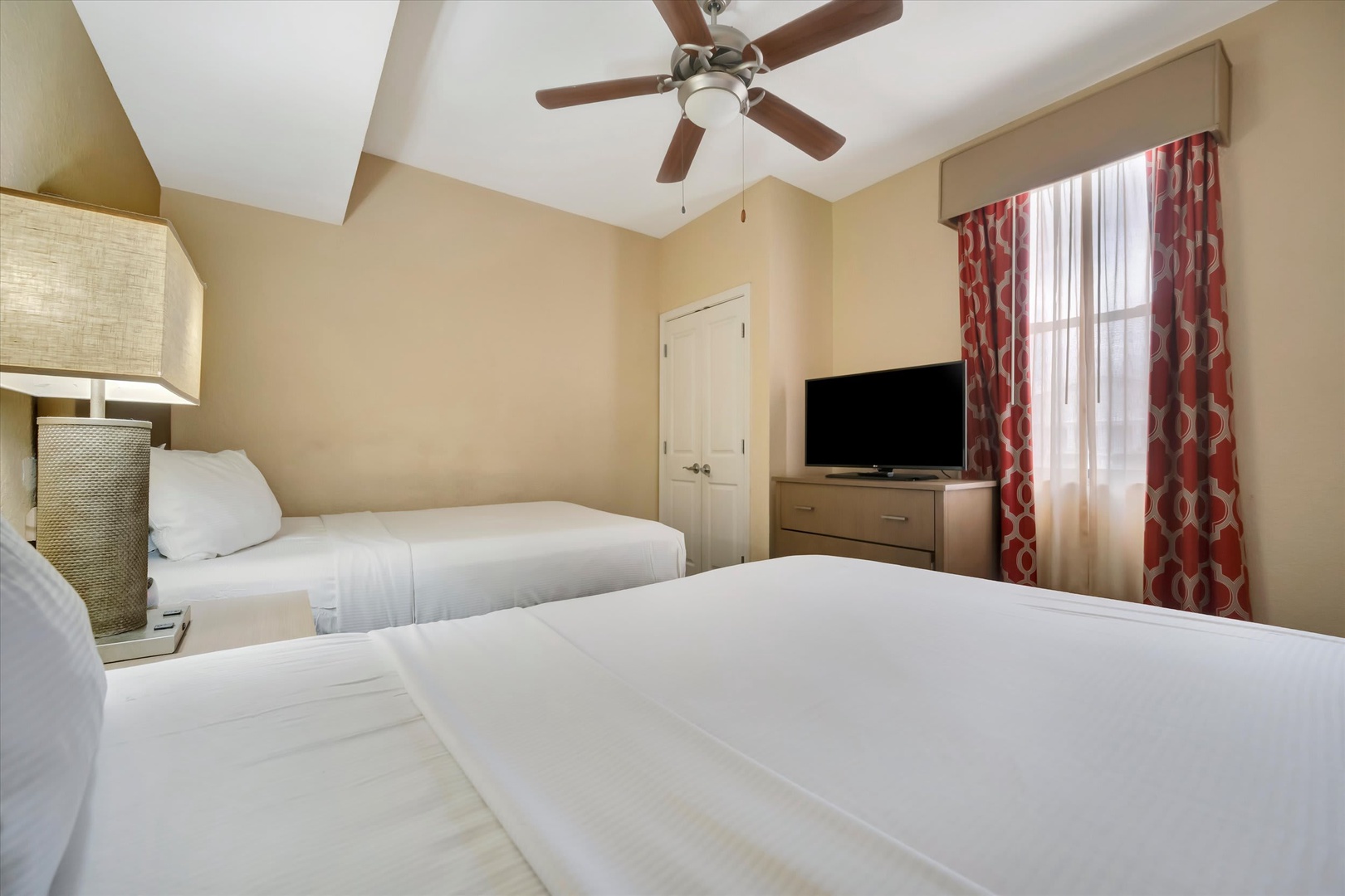 Sink into plush beds under a gently spinning ceiling fan, where bright natural light and warm tones create your serene retreat after adventure-filled days.