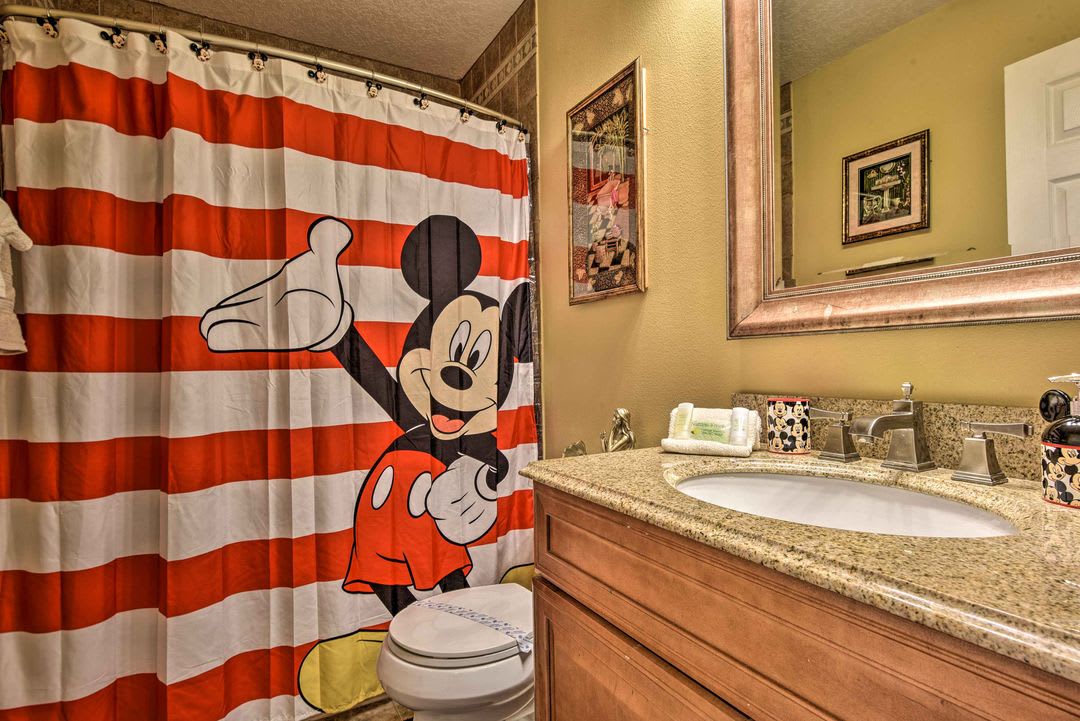 Step into your cheerful bathroom featuring Mickey-themed décor, a spacious vanity with granite countertop, and fun, family-friendly touches that add a magical vibe to your morning routine.