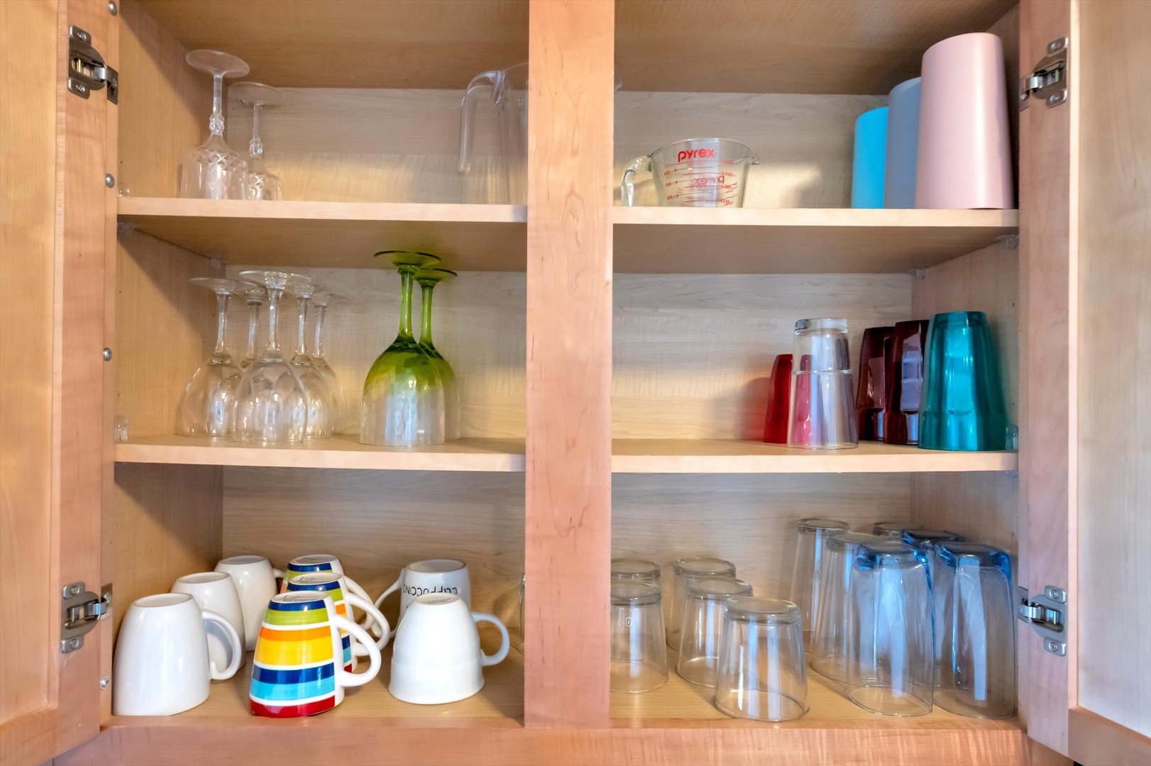 Everything you need for your morning coffee or evening drinks is thoughtfully arranged and ready. Open the cabinet doors and find colorful mugs, glassware, and cheerful tumblers waiting for you.