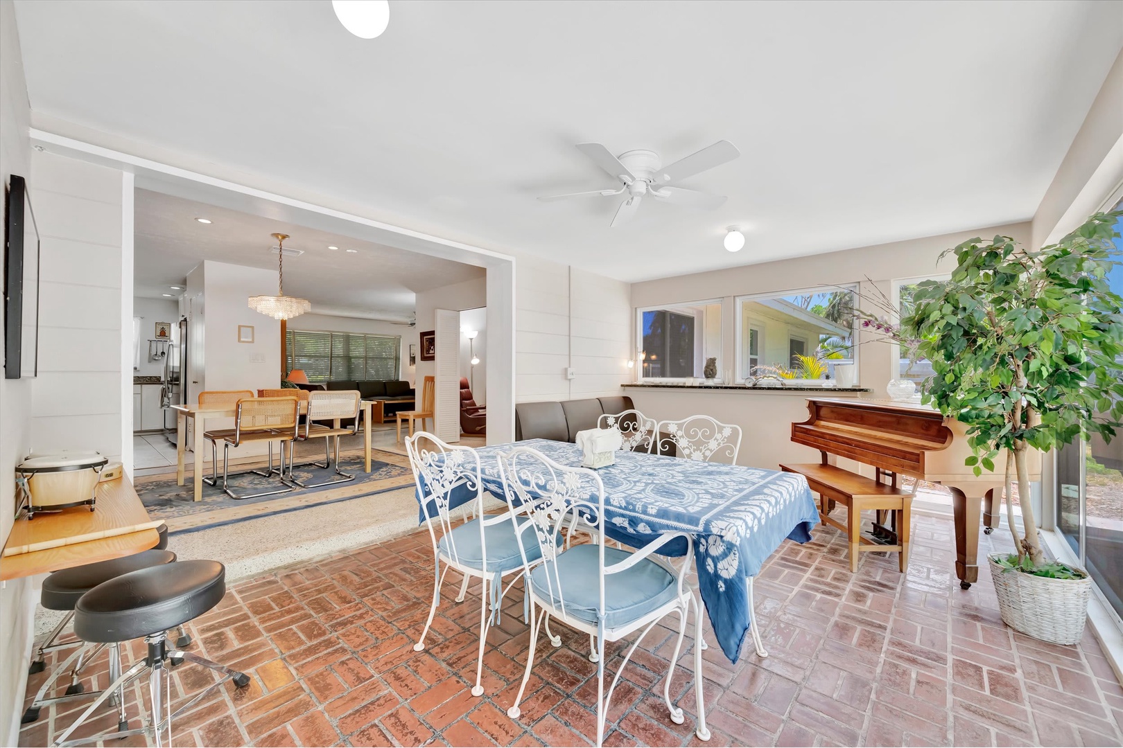 Gather with loved ones in this charming dining space where brick floors meet elegant seating. Your indoor-outdoor retreat features a piano for entertainment and flows seamlessly to the open kitchen and living area beyond.