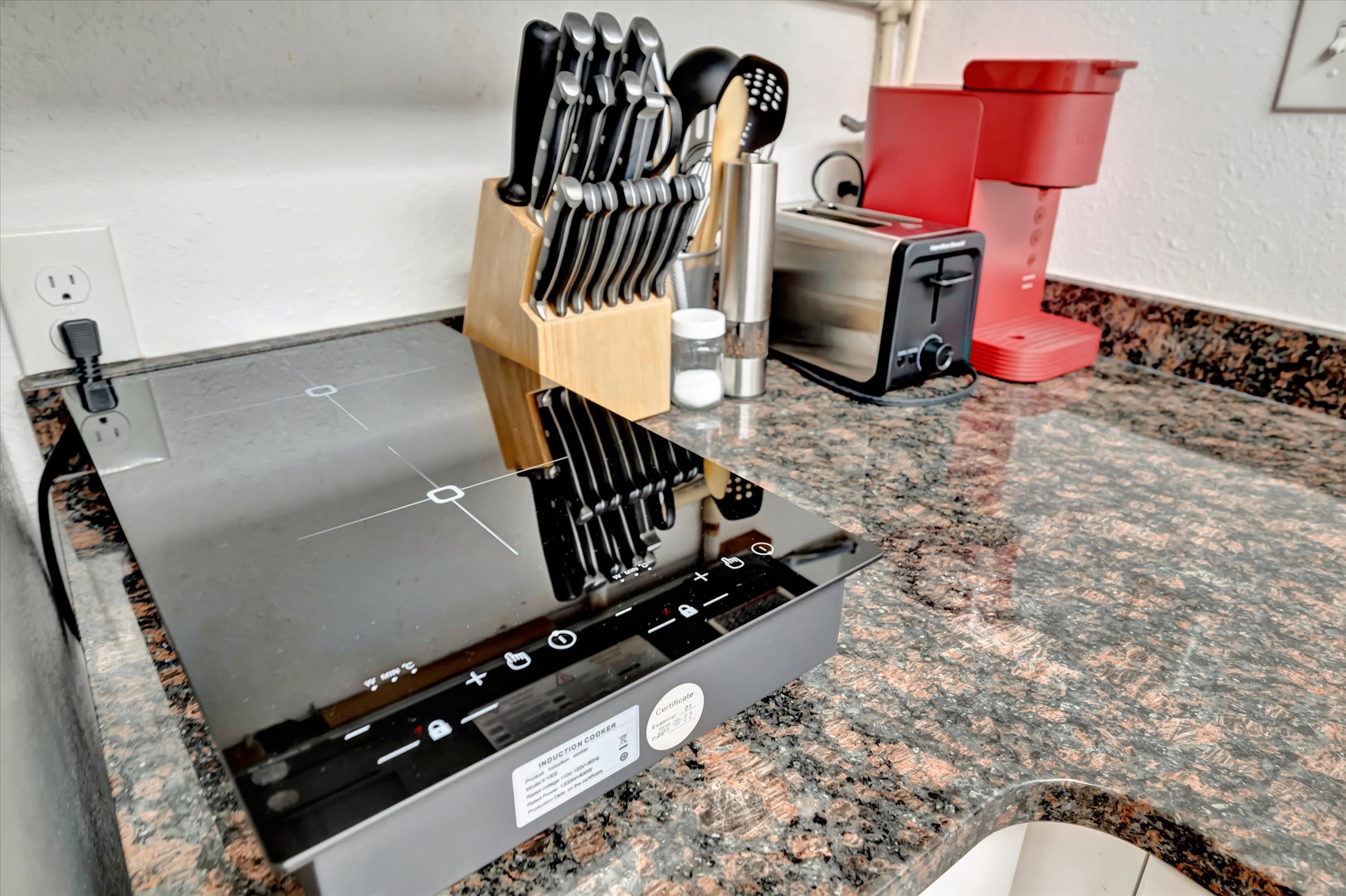 Your fully equipped kitchen features modern appliances, including a sleek induction cooktop, coffee maker, toaster, and a complete knife set—everything you need to feel at home while preparing your favorite meals.