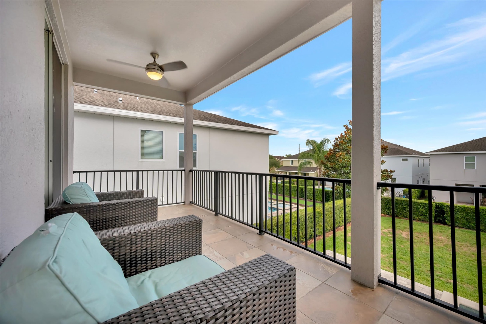 Relax in your private covered balcony with cushioned seating, ceiling fan, and views of the lush residential neighborhood—perfect for morning coffee or unwinding after a day of exploring.