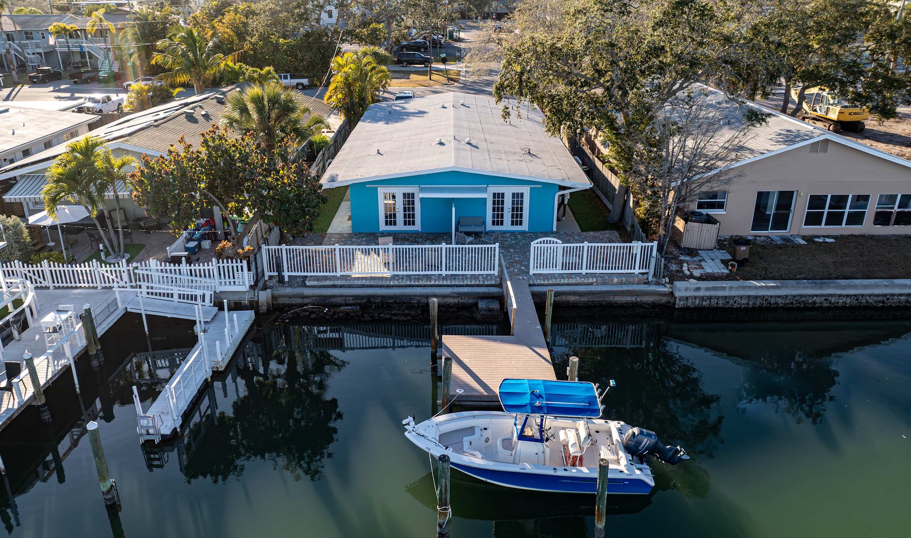 An aerial view of a waterfront property with a private dock, boat slip, and canal access in a peaceful residential neighborhood.