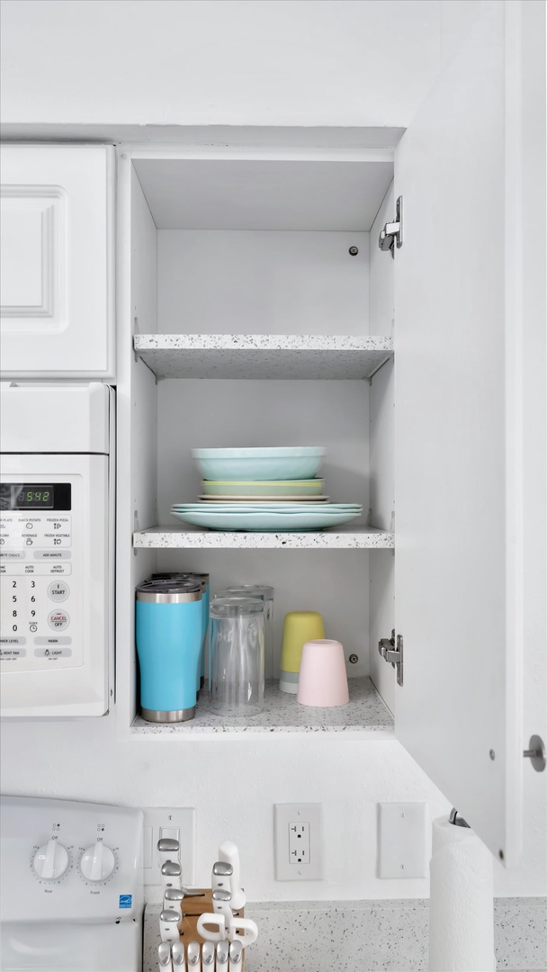 Your bright kitchen comes stocked with essentials, including fresh plates and tumblers ready for your morning coffee or snacks.