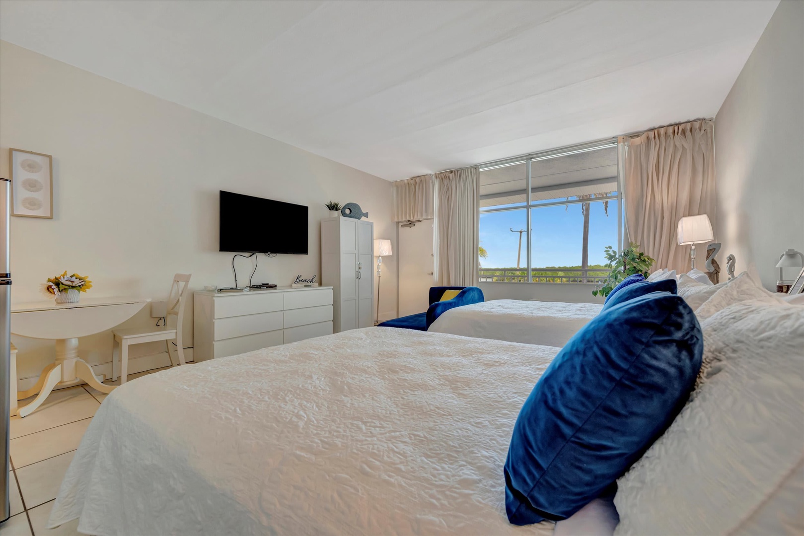 Wake up to natural light flooding through your windows, highlighting crisp white linens and coastal blue accents. Your serene bedroom offers peaceful views beyond, creating the perfect retreat after a day of exploring.