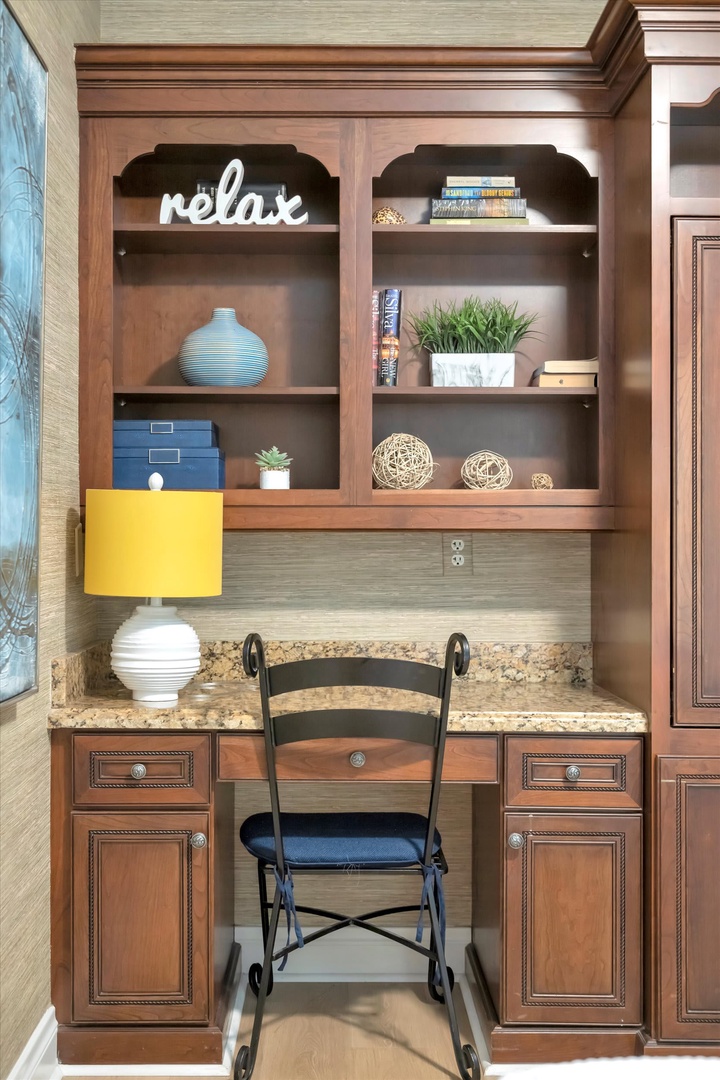 Your own personal workspace awaits—a thoughtfully designed nook with warm wood cabinetry, granite countertop, and custom shelving that invites you to settle in with a book or plan your next adventure.