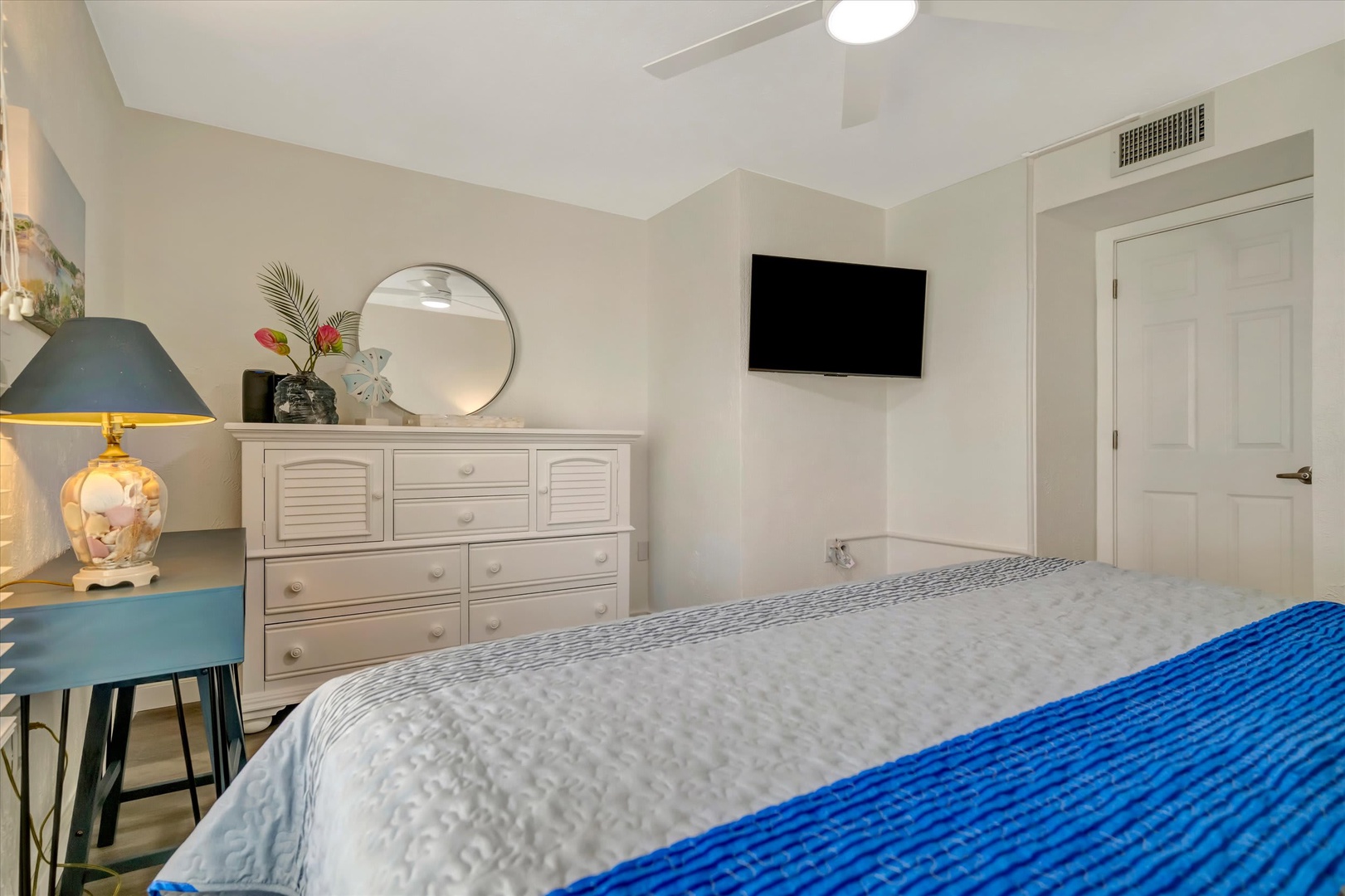 Unwind in your bright, serene bedroom with plush bedding, thoughtful coastal touches, and a wall-mounted TV for your evening downtime.