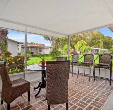 Step out onto your covered patio and settle into wicker seating surrounded by lush greenery. The brick flooring leads to a peaceful lawn, perfect for morning coffee or evening relaxation.