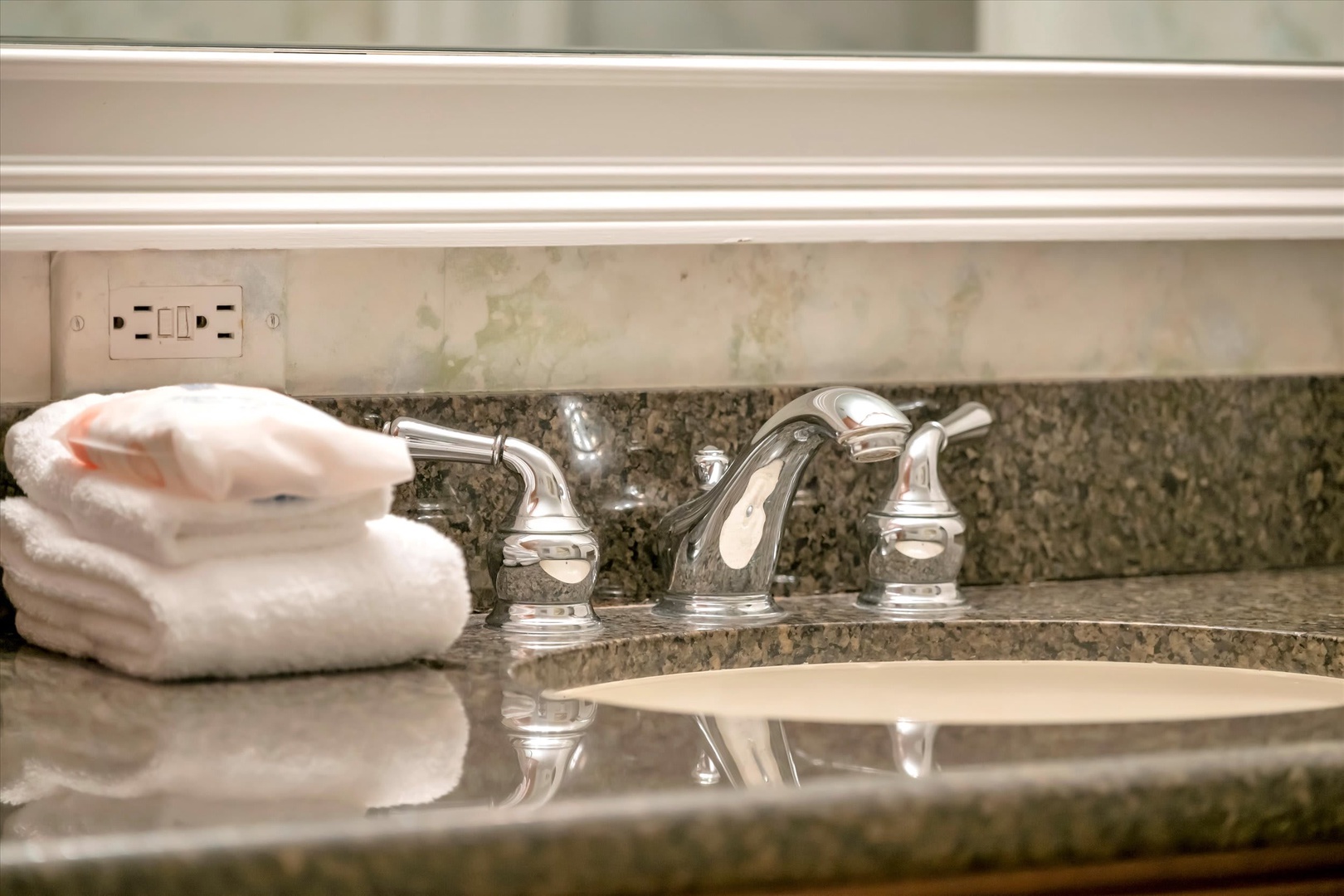 Your bathroom features gleaming fixtures and freshly rolled towels on elegant granite countertops, ready for your arrival.