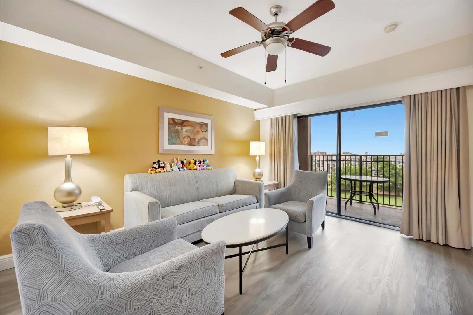 Settle into your bright, welcoming living space with plush seating and a gentle ceiling fan overhead. Step outside to your private balcony and take in the peaceful greenery stretching out before you.